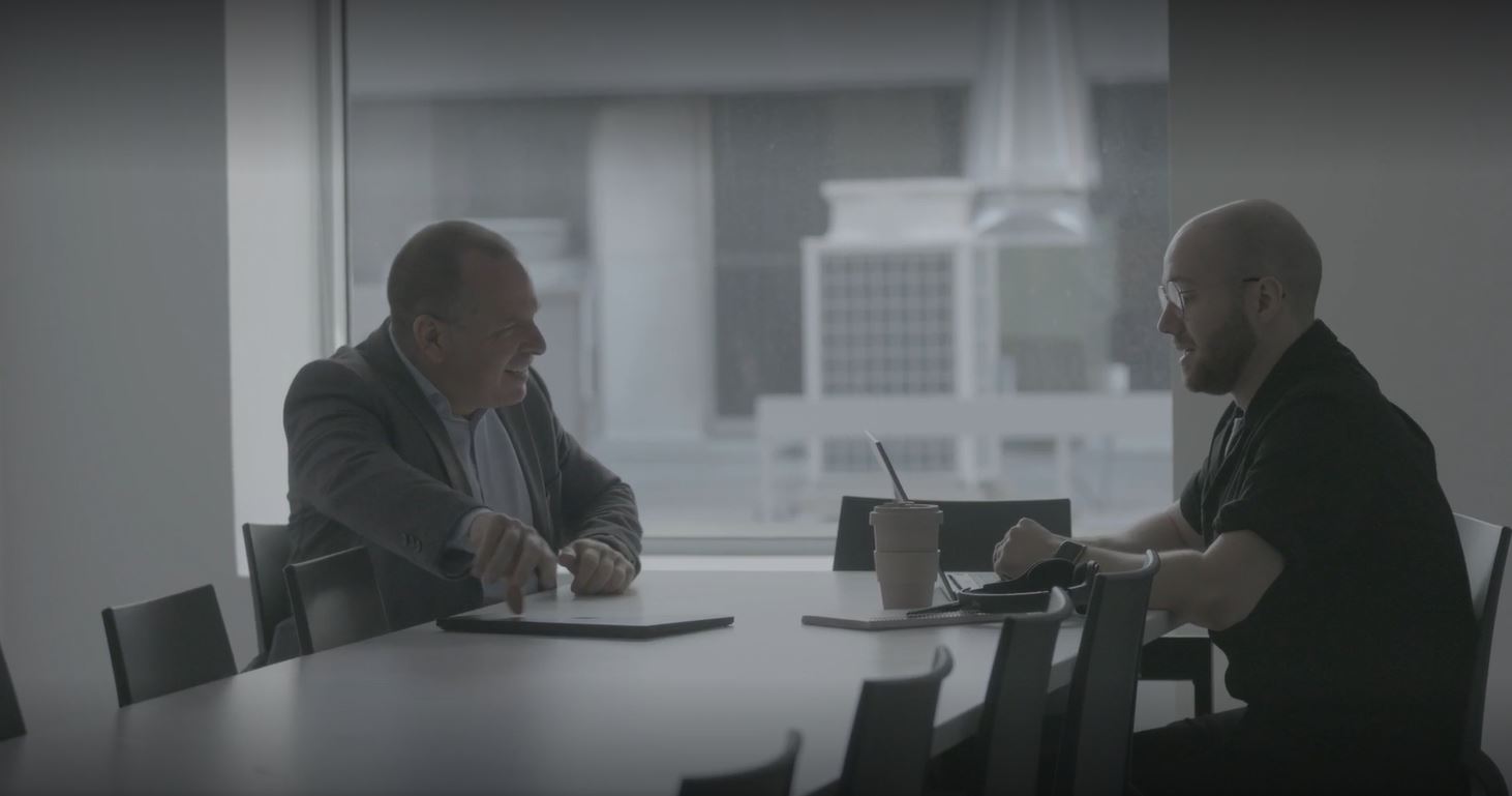 Deux hommes discutant à une table de bureau.