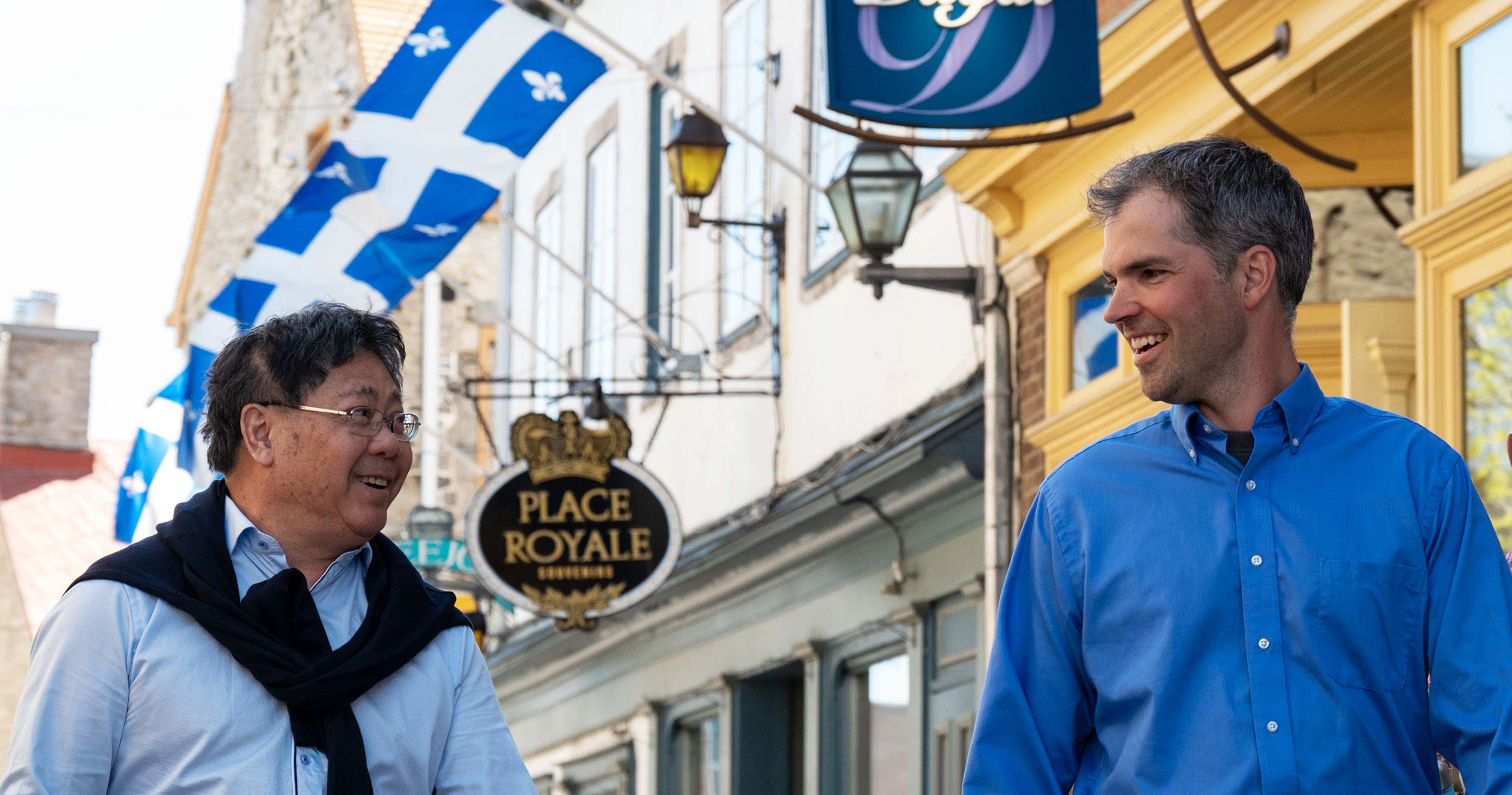 Two smiling men walking through downtown.